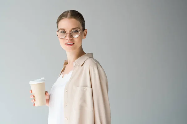 Mulher sorridente elegante com xícara de papel de café isolado em cinza — Fotografia de Stock