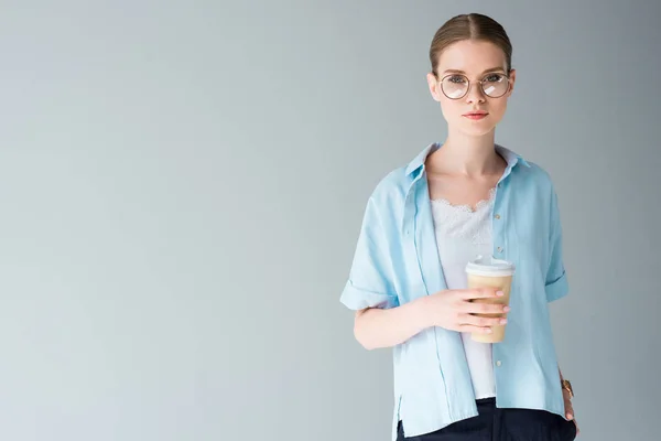 Schöne junge Frau mit Pappbecher Kaffee isoliert auf grau — Stockfoto