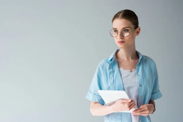 Attraktive junge Frau mit Tablette schaut isoliert von grau weg — Stockfoto