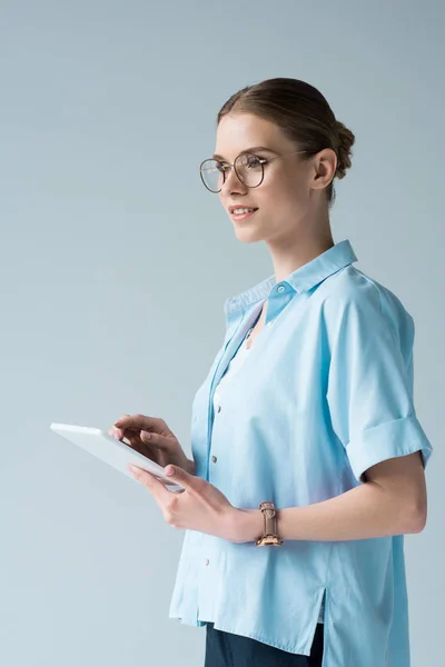 Jeune femme heureuse utilisant comprimé isolé sur gris et détournant les yeux — Photo de stock