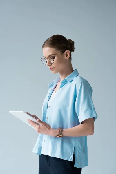 Atractiva mujer joven usando tableta aislada en gris - foto de stock