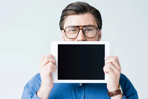 Jeune homme couvrant la moitié du visage avec une tablette avec écran blanc isolé sur blanc — Photo de stock