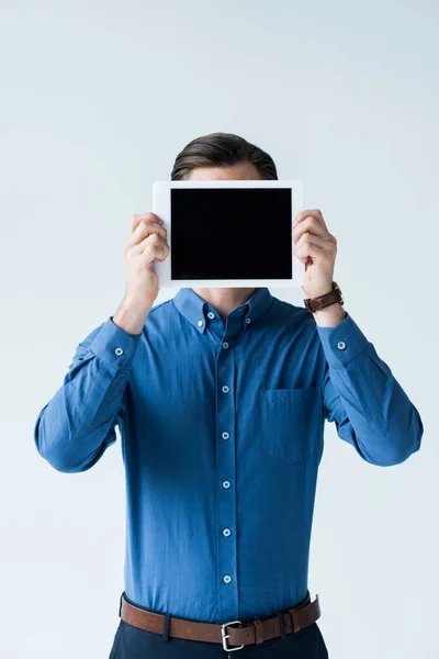 Hombre elegante que cubre la cara con la tableta con la pantalla en blanco aislado en blanco - foto de stock