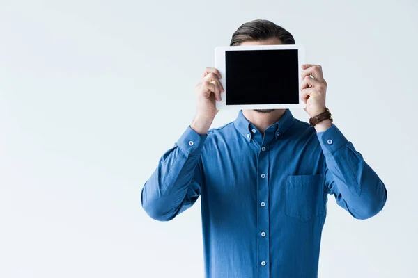 Hombre que cubre la cara con la tableta con la pantalla en blanco aislado en blanco - foto de stock