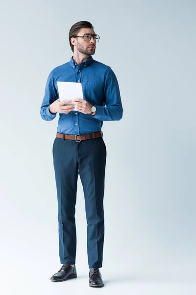 Selbstbewusster junger Mann in stilvoller Kleidung mit Tablet auf weißem Grund — Stockfoto