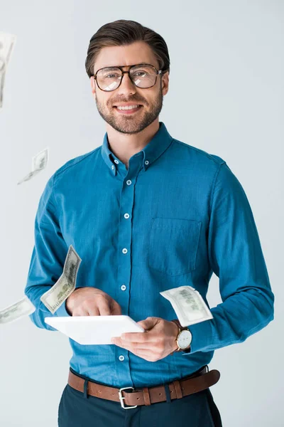 Money falling around young man with tablet isolated on white — Stock Photo