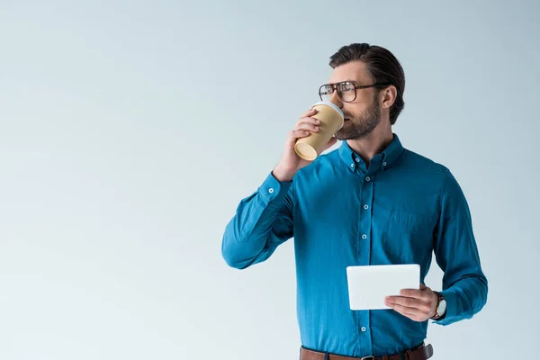 Привлекательный молодой человек с бумажной чашкой кофе и таблетки изолированы на белом — стоковое фото