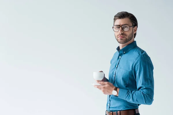 Schöner junger Mann mit einer Tasse Kaffee, der in die Kamera schaut, isoliert auf weiß — Stockfoto