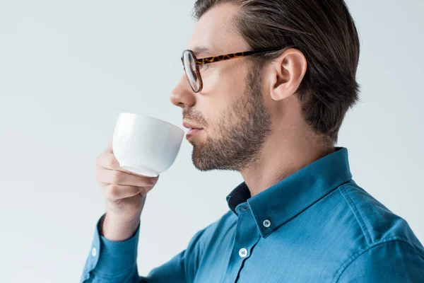 Vista lateral del joven bebiendo café de la taza aislada en blanco - foto de stock