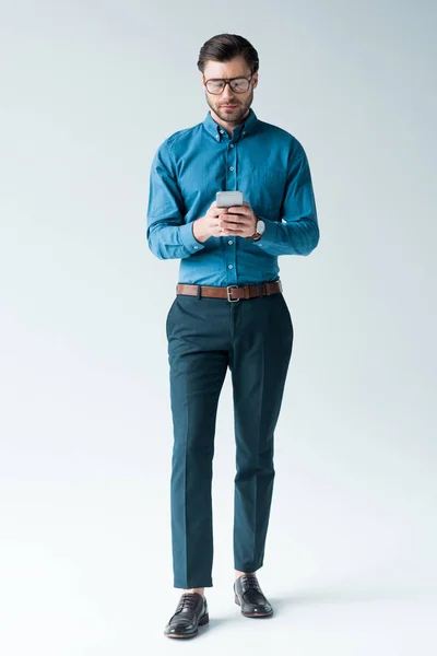 Handsome young man in stylish clothes using smartphone on white — Stock Photo