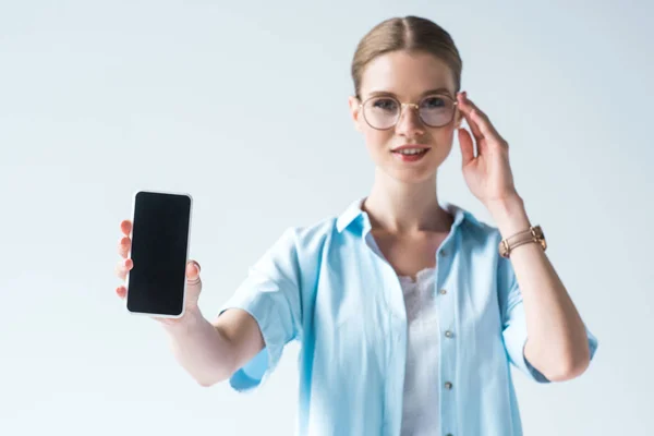 Hermosa mujer joven sosteniendo teléfono inteligente con pantalla en blanco aislado en blanco - foto de stock