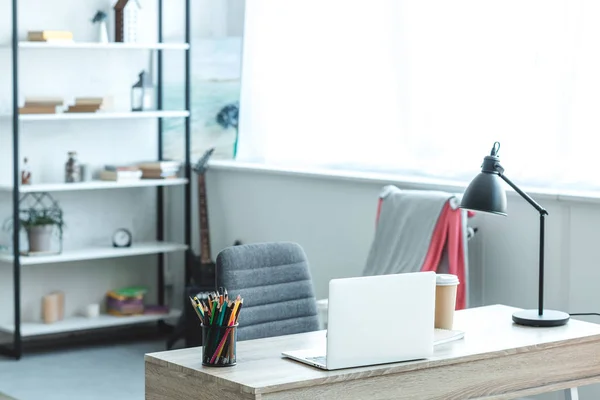 Laptop e café para ir em mesa de madeira em quarto acolhedor com interior moderno — Fotografia de Stock