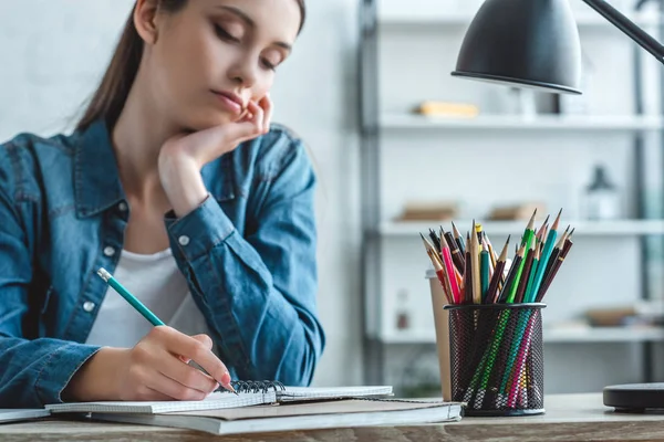Обрізаний знімок нудно дівчина писати в Блокноті і навчання на дому — стокове фото