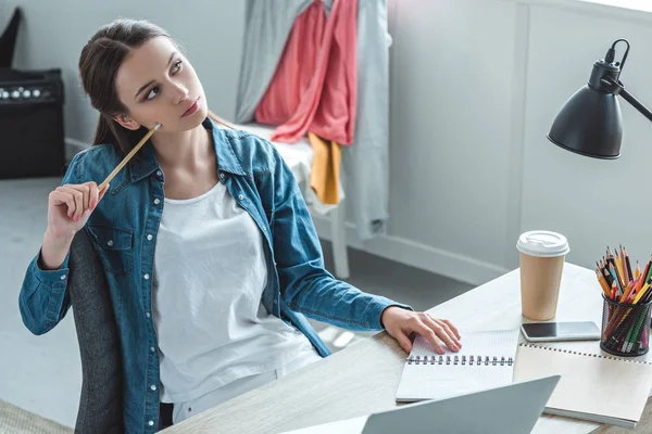 Pensive girl holding pencil and looking away while studying at home — Stock Photo