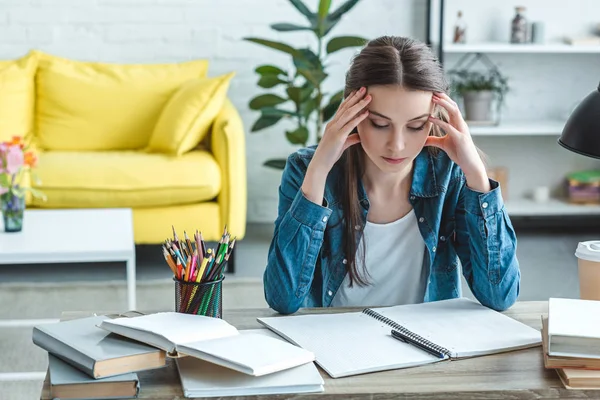 Concentrated girl with headache sitting at desk and studying at home — Stock Photo