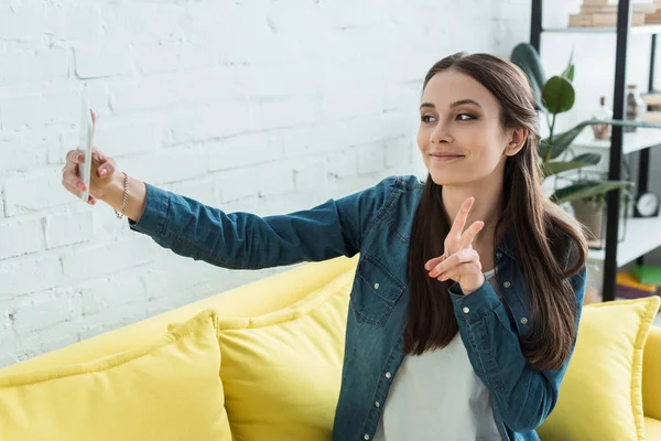 Hermosa chica feliz tomando selfie con teléfono inteligente en casa - foto de stock