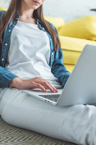 Обрезанный снимок молодой женщины с помощью ноутбука, сидя дома — стоковое фото