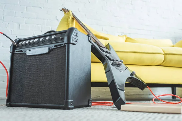 Chitarra elettrica e altoparlante in piedi sul pavimento vicino al divano — Foto stock
