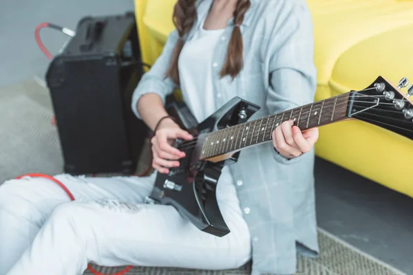 Vista ritagliata di ragazza che suona la chitarra elettrica a casa — Foto stock