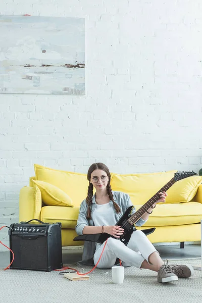 Atractiva chica adolescente tocando la guitarra eléctrica en sala de estar - foto de stock