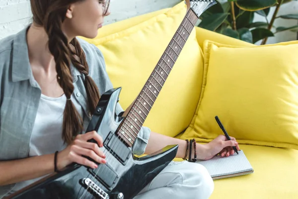 Attractive teen girl playing electric guitar and writing song — Stock Photo