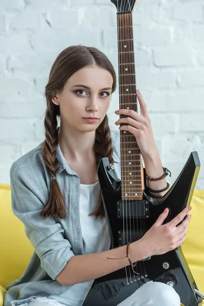 Attractive teen musician with electric guitar sitting on sofa — Stock Photo