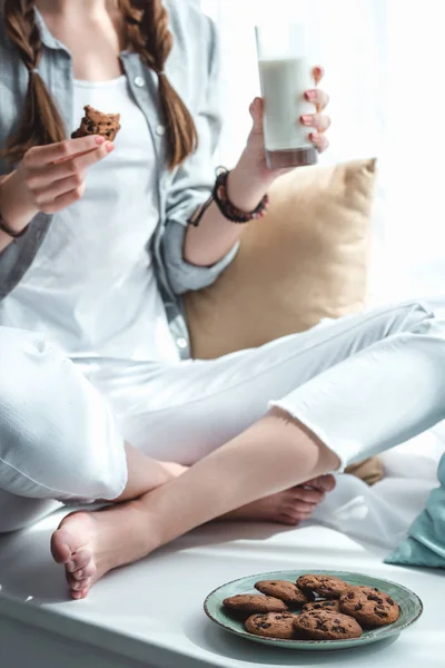 Cropped view of girl eating cookies with milk — Stock Photo