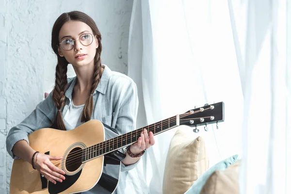 Schönes Teenie-Mädchen spielt Akustikgitarre am Fenster — Stockfoto