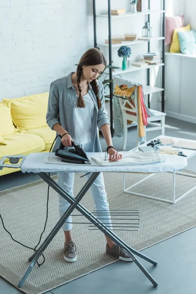 Attractive youth girl ironing in living room — Stock Photo