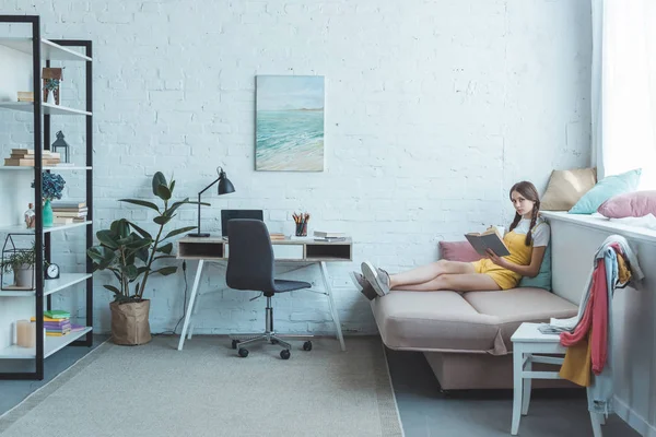 Teen girl reading book in modern living room — Stock Photo