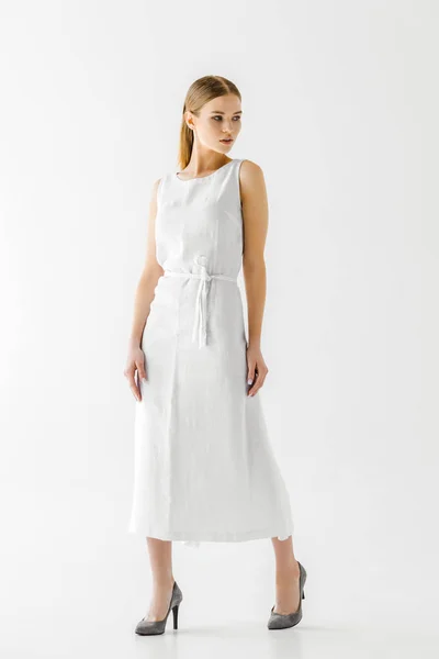 Atractiva mujer en vestido de lino blanco mirando hacia otro lado aislado sobre fondo gris - foto de stock