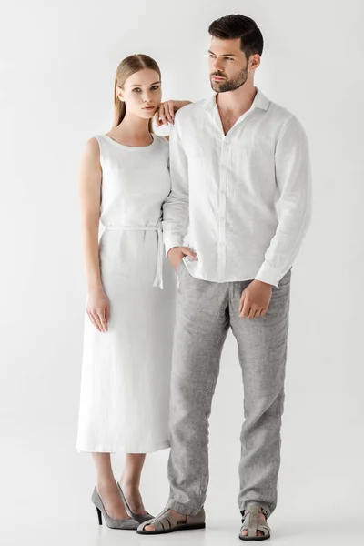 Young woman in linen white dress embracing boyfriend with hand in pocket isolated on grey background — Stock Photo