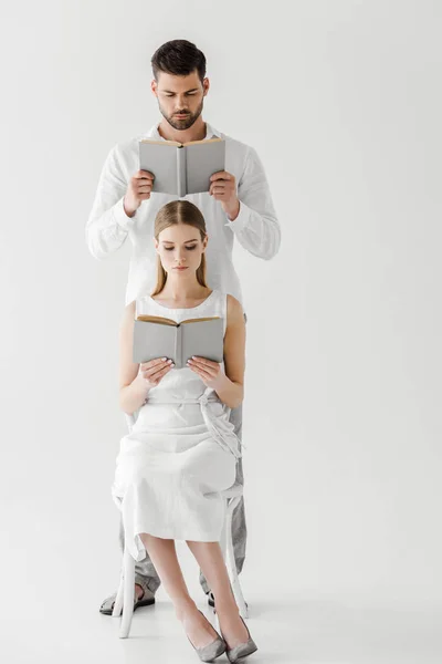 Целенаправленная пара в льняной одежде читает книги изолированные на сером фоне — стоковое фото