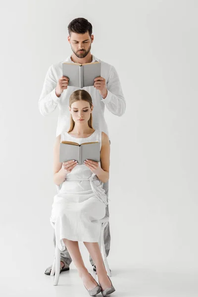 Pareja enfocada en ropa de lino leyendo libros aislados sobre fondo gris - foto de stock