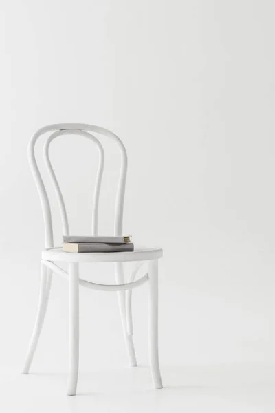 Vista frontale della sedia con due libri isolati su sfondo grigio — Foto stock