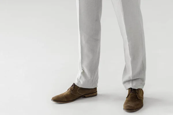 Обрезанное изображение мужской модели в льняных брюках и замшевых туфлях, изолированных на сером фоне — стоковое фото