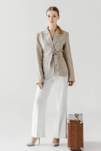 Stylish woman in linen jacket standing near vintage suitcase isolated on grey background — Stock Photo