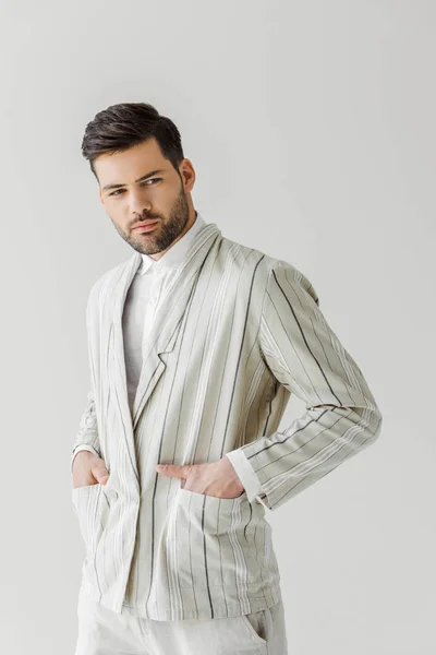 Joven guapo en chaqueta de rayas vintage con las manos en bolsillos aislados en blanco - foto de stock