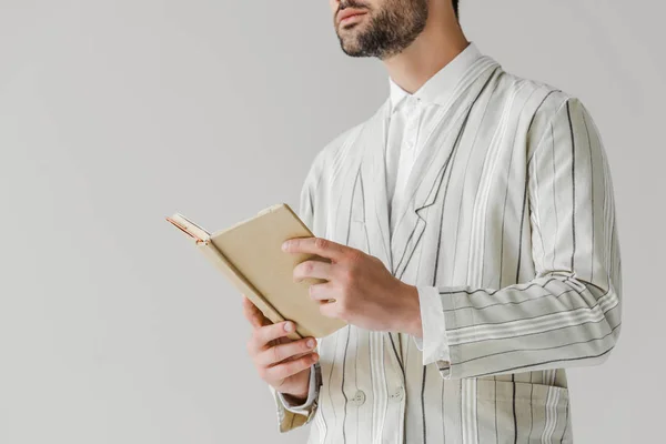 Cropped shot of young man in striped jacket holding book isolated on white — Stock Photo