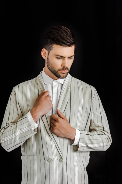 Schöner junger Mann in stylischer, gestreifter Jacke isoliert auf schwarz — Stockfoto