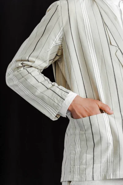 Cropped shot of man with hand in pocket of stylish striped jacket isolated on black — Stock Photo