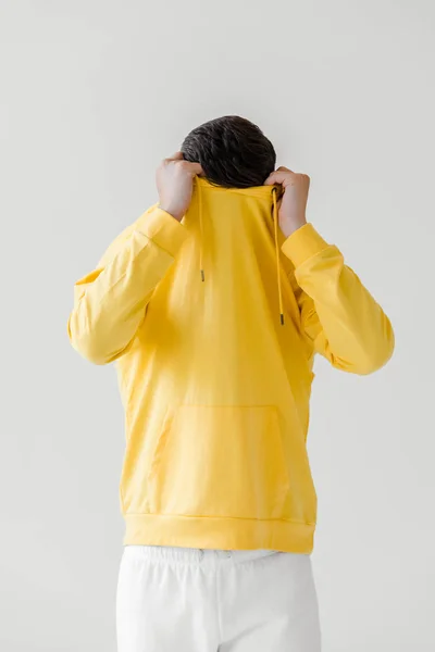 Young man taking off yellow hoodie isolated on white — Stock Photo