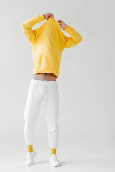 Young man taking off yellow hoodie on white — Stock Photo