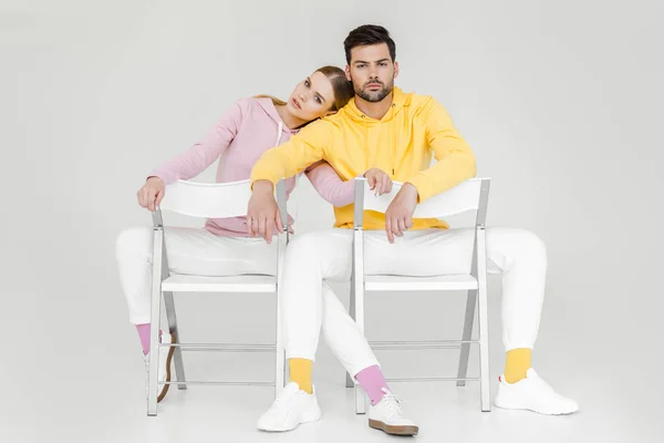 Couple of models sitting on chairs and looking at camera on white — Stock Photo