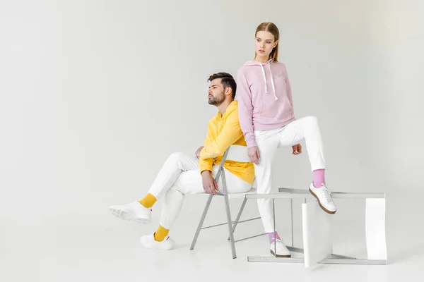 Modelos masculinos e femininos jovens em capuzes rosa e amarelo no branco — Fotografia de Stock