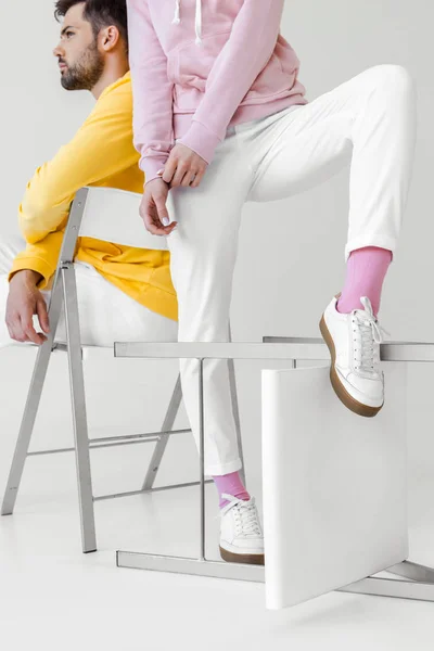 Cropped shot of young male and female models in colorful hoodies on white — Stock Photo