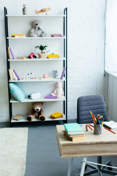 Books and toys on shelves and wooden table with school supplies — Stock Photo