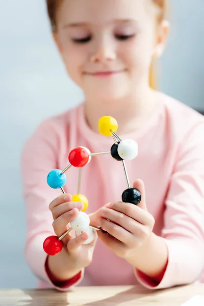 Foco seletivo de criança em idade escolar sorrindo segurando modelo molecular — Fotografia de Stock