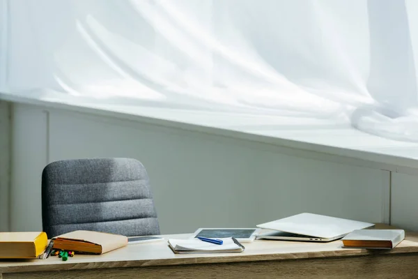 Tablet digital, laptop y libros sobre mesa de madera - foto de stock