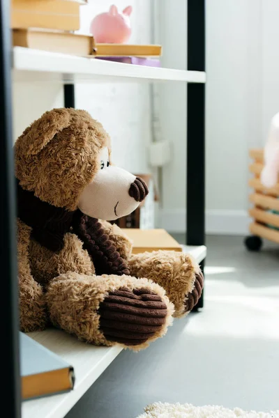 Vista de cerca de un hermoso oso de peluche y libros en estanterías en la habitación - foto de stock